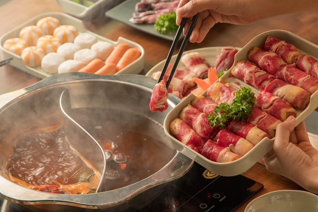 鸳鸯锅旁,用筷子夹起一盘卷好的牛肉片